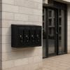 cassetta-postale-coreografica Cassetta postale nera 4 scomparti fissata al muro esterno di condominio moderno