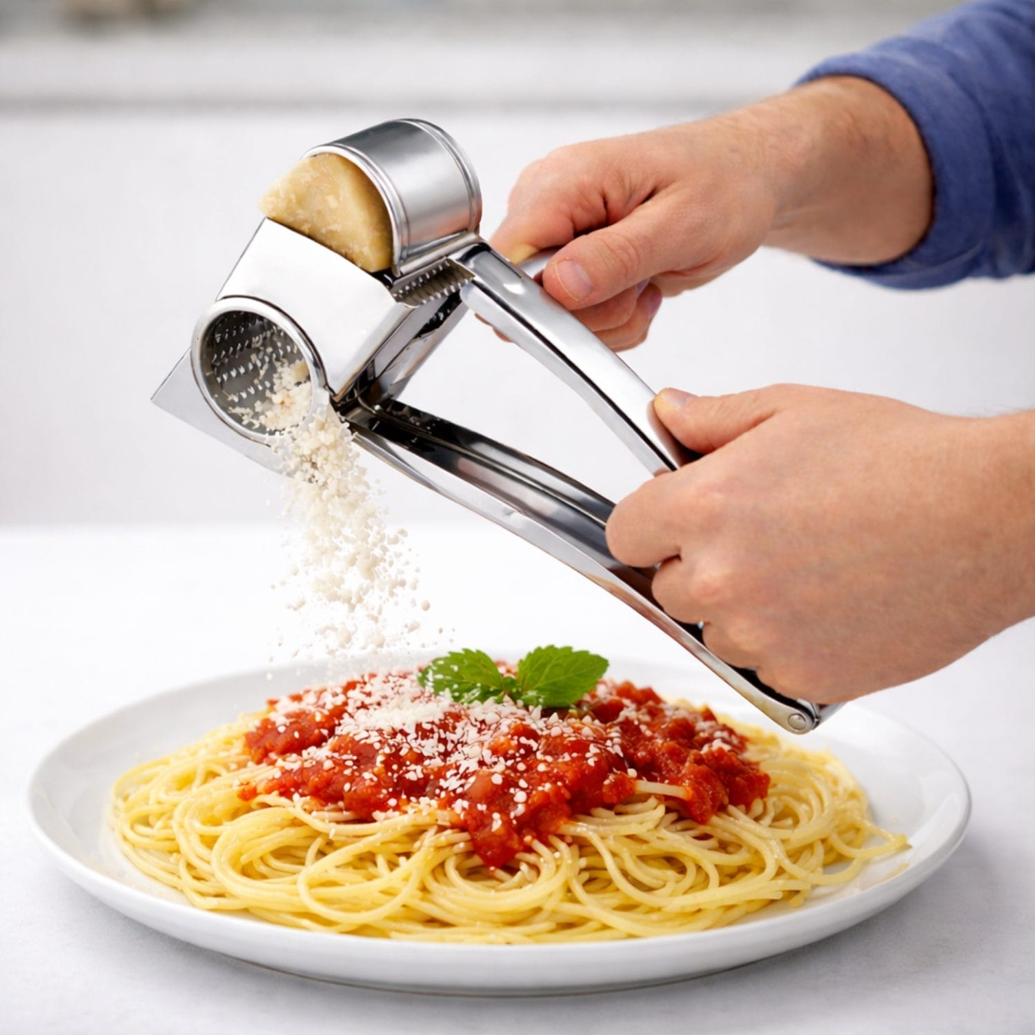 Grattugia manuale in acciaio inox in uso su pasta con formaggio grattugiato