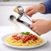 grattugia manuale Grattugia manuale in acciaio inox in uso su pasta con formaggio grattugiato