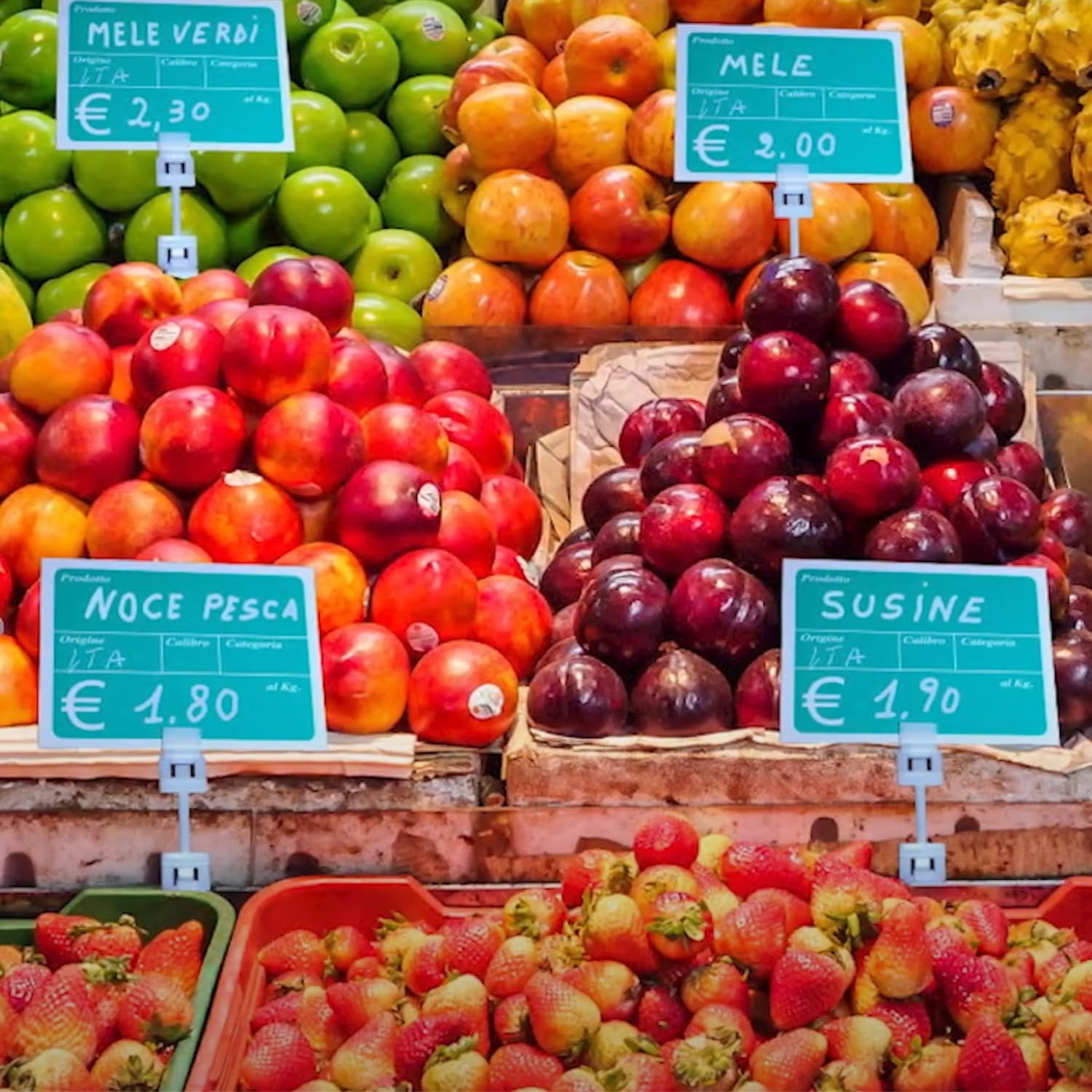 Cartellino ortofrutta con prezzo esposto su banco di mele e frutta fresca