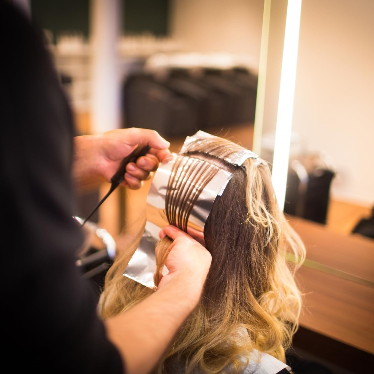 Parrucchiere applica fogli di alluminio per meches e trattamenti colore professionali