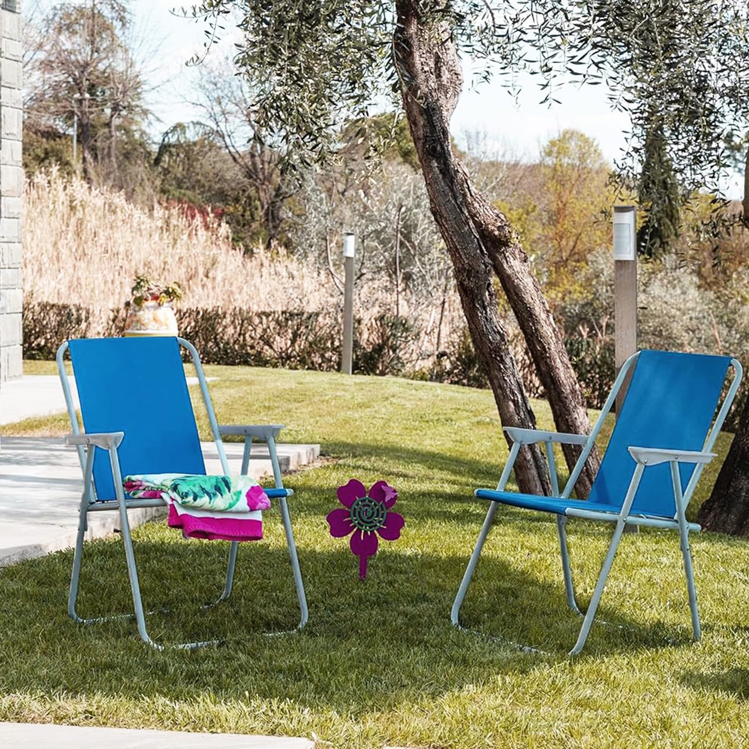 Sedie da spiaggia pieghevoli blu posizionate in giardino sotto un albero