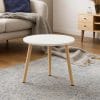 Tavolino basso rotondo in legno chiaro e piano bianco per salotto moderno