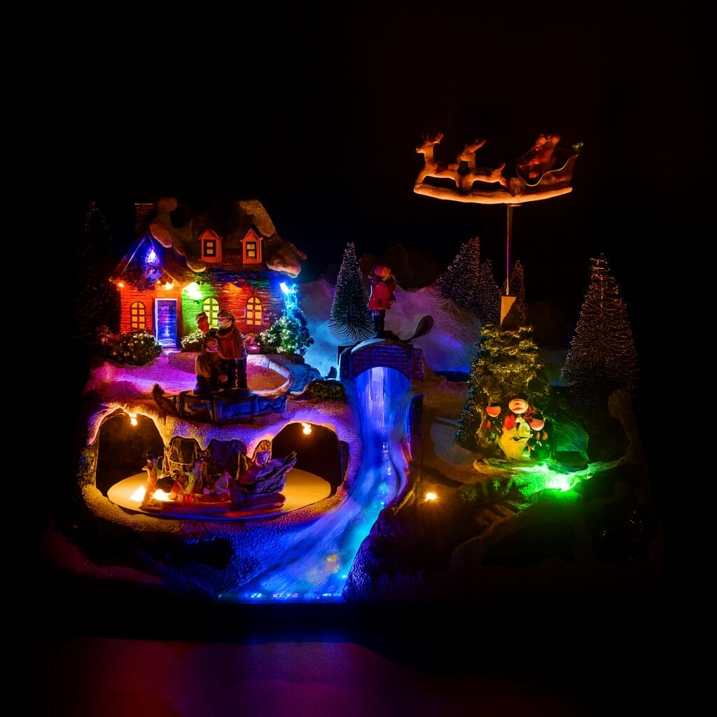 Decorazione natalizia luminosa con casa innevata, figure in movimento e slitta di Babbo Natale Paluplus