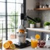 spremiagrumi nero coreografica Spremiagrumi manuale nero in acciaio inox in funzione su piano cucina con arance spremute